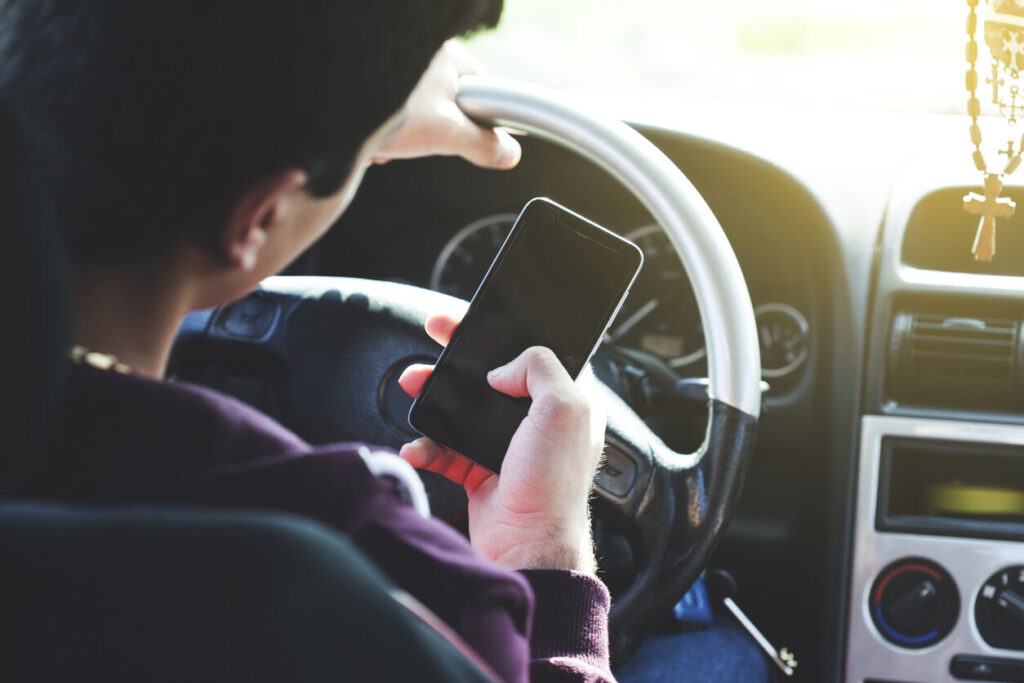person operating mobile phone while driving