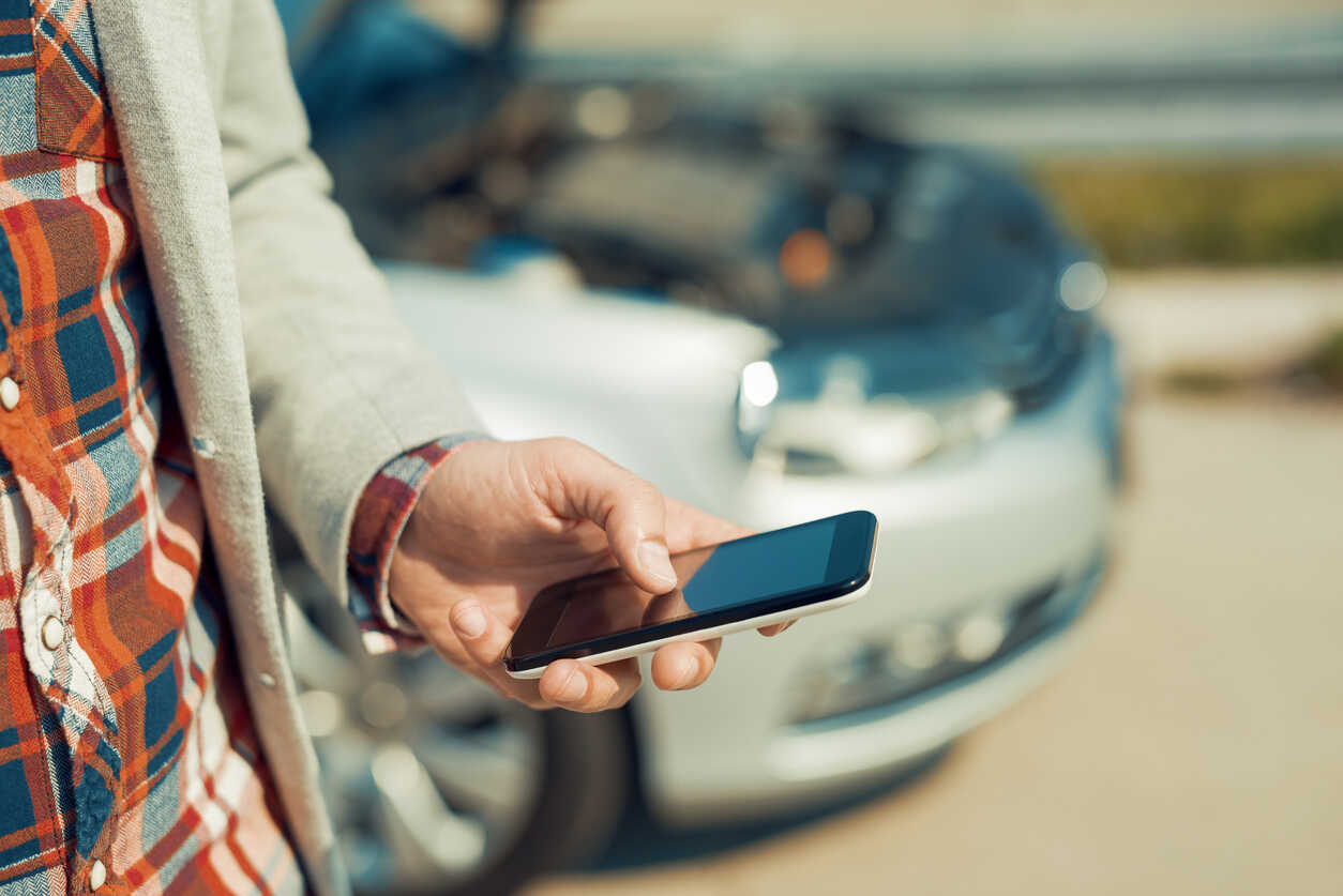 Man using smartphone after rental car accident in traffic
