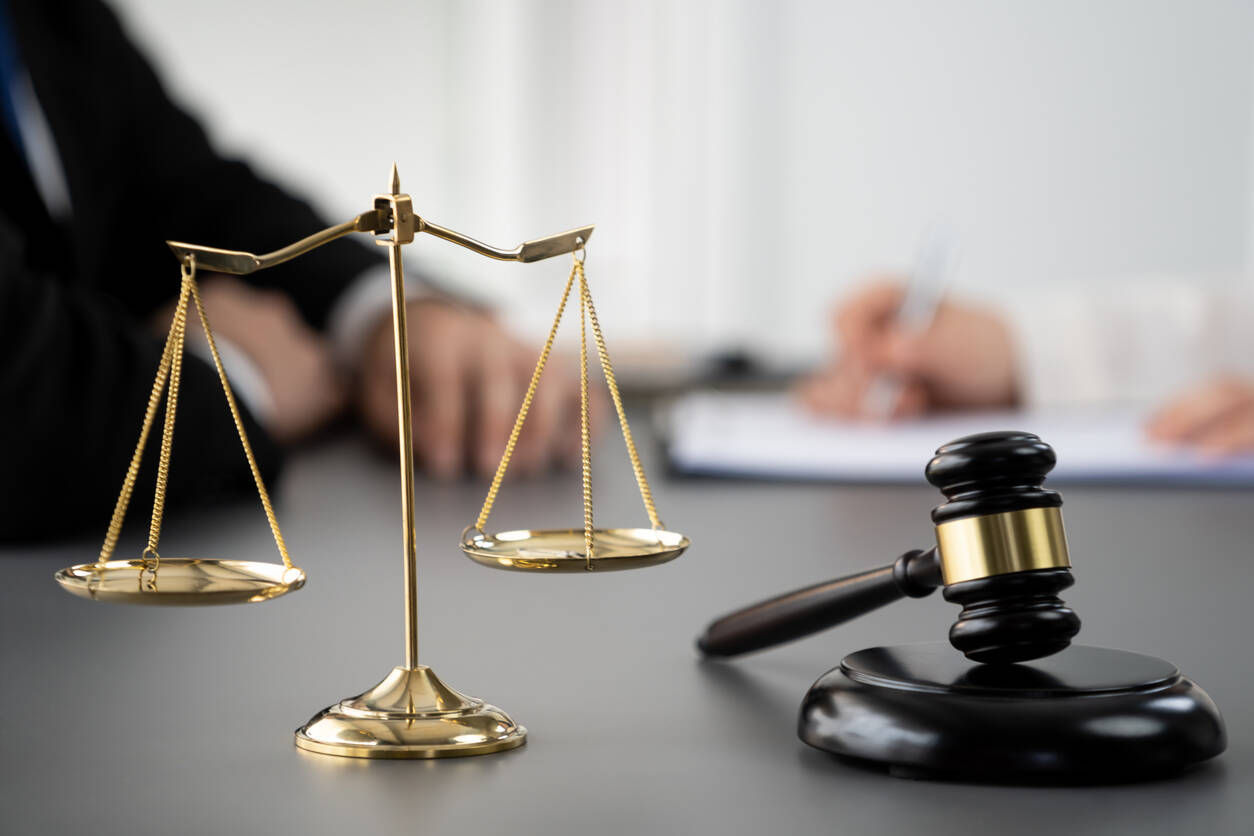 lawyer sitting and Judge gavel and Gold brass Scales of justice on the table