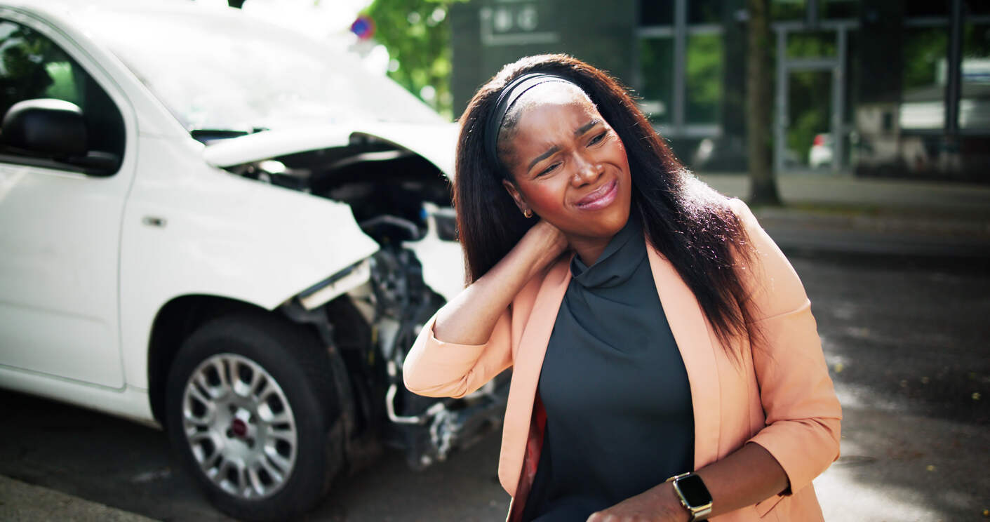 A white rideshare car with a company logo on the door is shown on a city street, with a pedestrian standing on the sidewalk. The image represents a scenario where a non-passenger, such as a bystander or pedestrian, is involved in an injury accident with a rideshare vehicle.