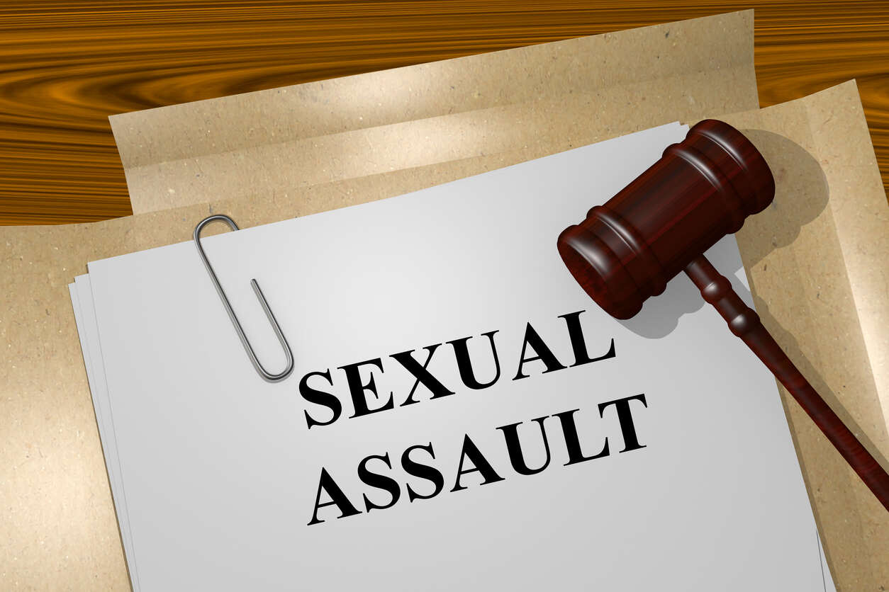 Close-up of a legal brief or report titled 'SEXUAL ASSAULT' next to a wooden gavel, representing the pursuit of justice by sexual assault attorneys.