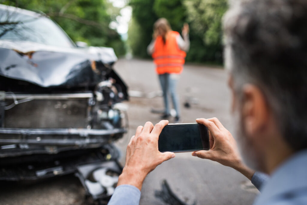 man taking pictures for car accident evidence